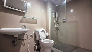 Uma casa de banho moderna com chuveiro em cabine de vidro, sanita e lavatório.