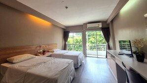 Une chambre d’hôtel avec deux lits, un bureau et une vue sur la verdure.