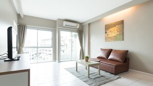 Un salon moderne avec un canapé, une table basse et un téléviseur posé sur un meuble.