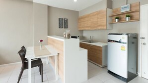 Une cuisine moderne avec un plan de travail blanc, des armoires en bois et un réfrigérateur encastré.