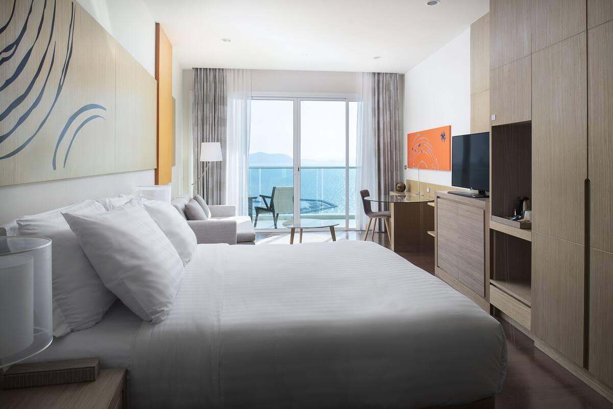 Ein modernes Hotelzimmer mit einem großen Bett, einem Schreibtisch, einem Stuhl und einem Fernseher.