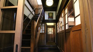 A wooden staircase with a metal handrail leading to a landing with a framed picture. - Hakodate Classic Hotels (Hakodate)