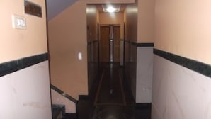 A corridor with a marble floor, a handrail, and a door at the end. - Hotel Palms (Navi Mumbai)