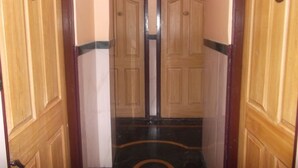 A hallway with wooden doors and a black and gold patterned floor. - Hotel Palms (Navi Mumbai)