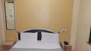 A room with a bed, two bedside tables, a wall-mounted telephone, and a window with a view. - Hotel Palms (Navi Mumbai)
