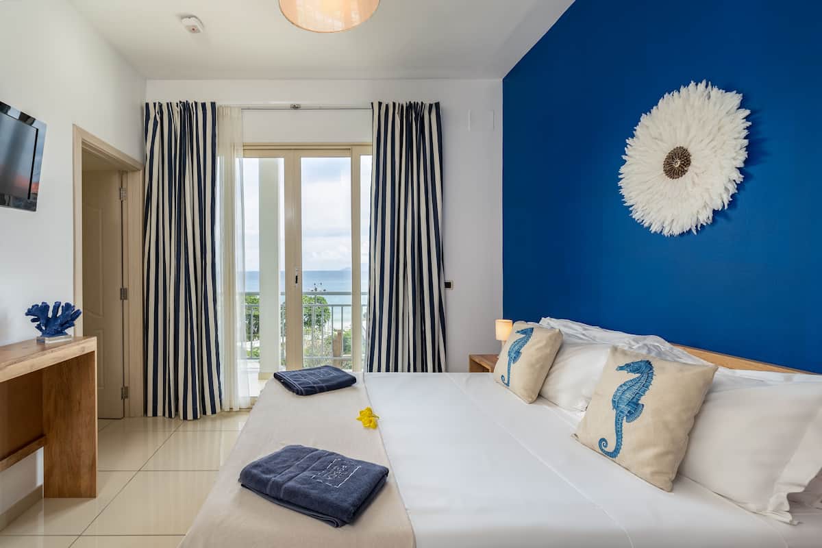 A hotel room with a bed, curtains, a desk, and a view of the outdoors.