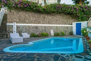 Una piscina al aire libre, sillones reclinables de piscina