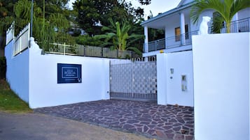 Una propiedad amurallada con un acceso empedrado de piedra, un letrero que dice "Villa Roscia" y un edificio blanco con balcón.