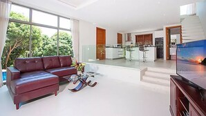 A modern living room with a sectional sofa, a glass coffee table, and a TV. - 2 Bedroom Pool Villa with Waterfall View SDV006-By Samui Dream Villas (Koh Samui)