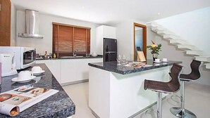 A modern kitchen with a central island, white cabinetry, a stainless steel range hood, and a black refrigerator. - 2 Bedroom Pool Villa with Waterfall View SDV006-By Samui Dream Villas (Koh Samui)