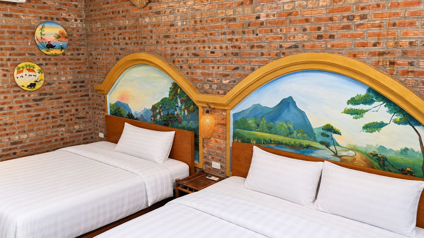 A room with two beds, brick walls, and a mural on the wall.