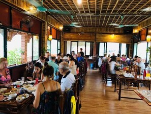 Un restaurant amb terres de fusta i parets de maó, amb taules i cadires disposades per dinar.
