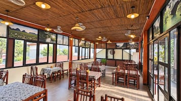 Un restaurante con techo de madera, ventanas amplias y mesas con manteles estampados.