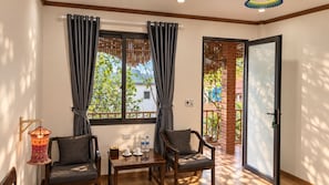 Una habitación con una mesa de madera, dos sillas, una ventana con cortinas, una puerta y una lámpara colgante.