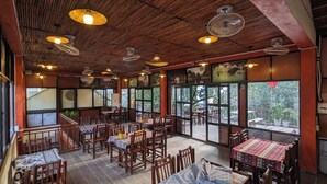 Un restaurante con muebles de madera, ventanas amplias y ventiladores de techo.