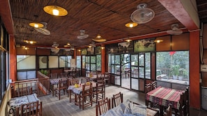 A restaurant with wooden furniture, large windows, and ceiling fans.