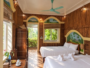 Una habitación con dos camas, ventilador de techo y vistas al exterior.
