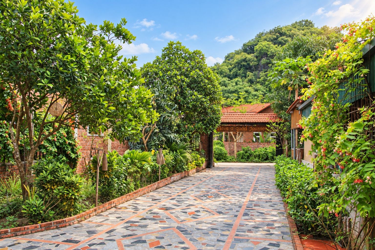 A paved pathway leading to a building with a red-tiled roof, surrounded by lush greenery and a brick wall.