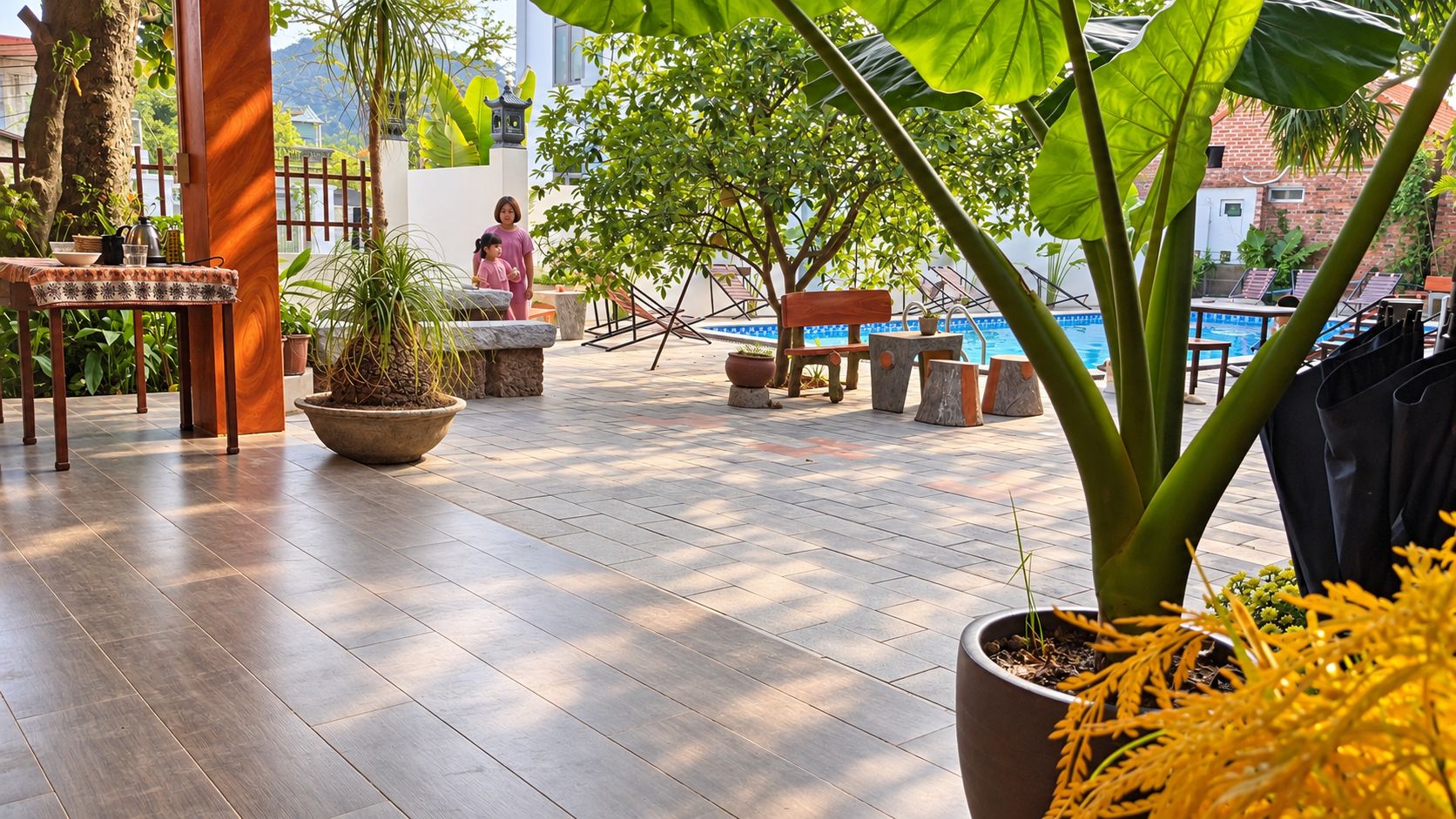 A spacious outdoor area with a pool, seating, and potted plants.