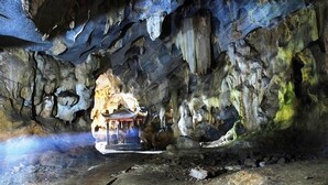 Una cueva con estalactitas y estalagmitas, un pequeño santuario y un elemento decorativo de agua.