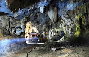 Eine Höhle mit Stalaktiten und Stalagmiten, ein kleiner Schrein und ein Wasserspiel.