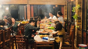 A group of people dining at a restaurant with wooden furniture and brick walls.