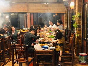 A group of people dining at a restaurant with wooden furniture and brick walls. - Ninh Binh Greenland Homestay (Hoa Lu)