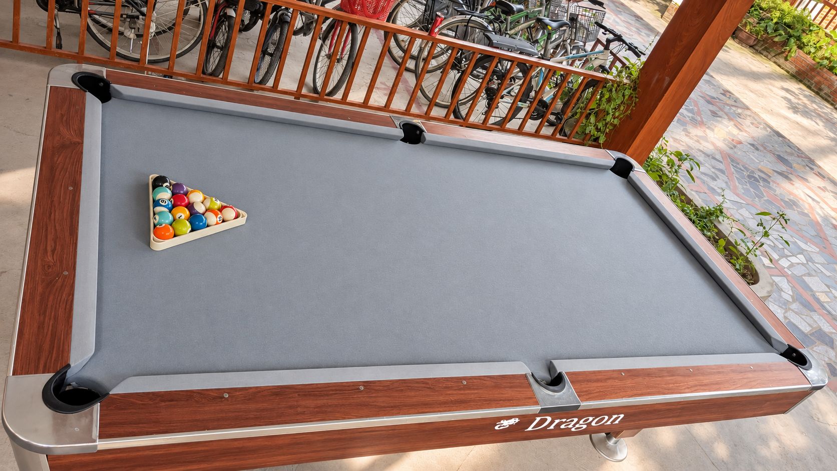 A pool table with a triangular rack of billiard balls, wooden frame, and a brand name 'Dragon' on the side.