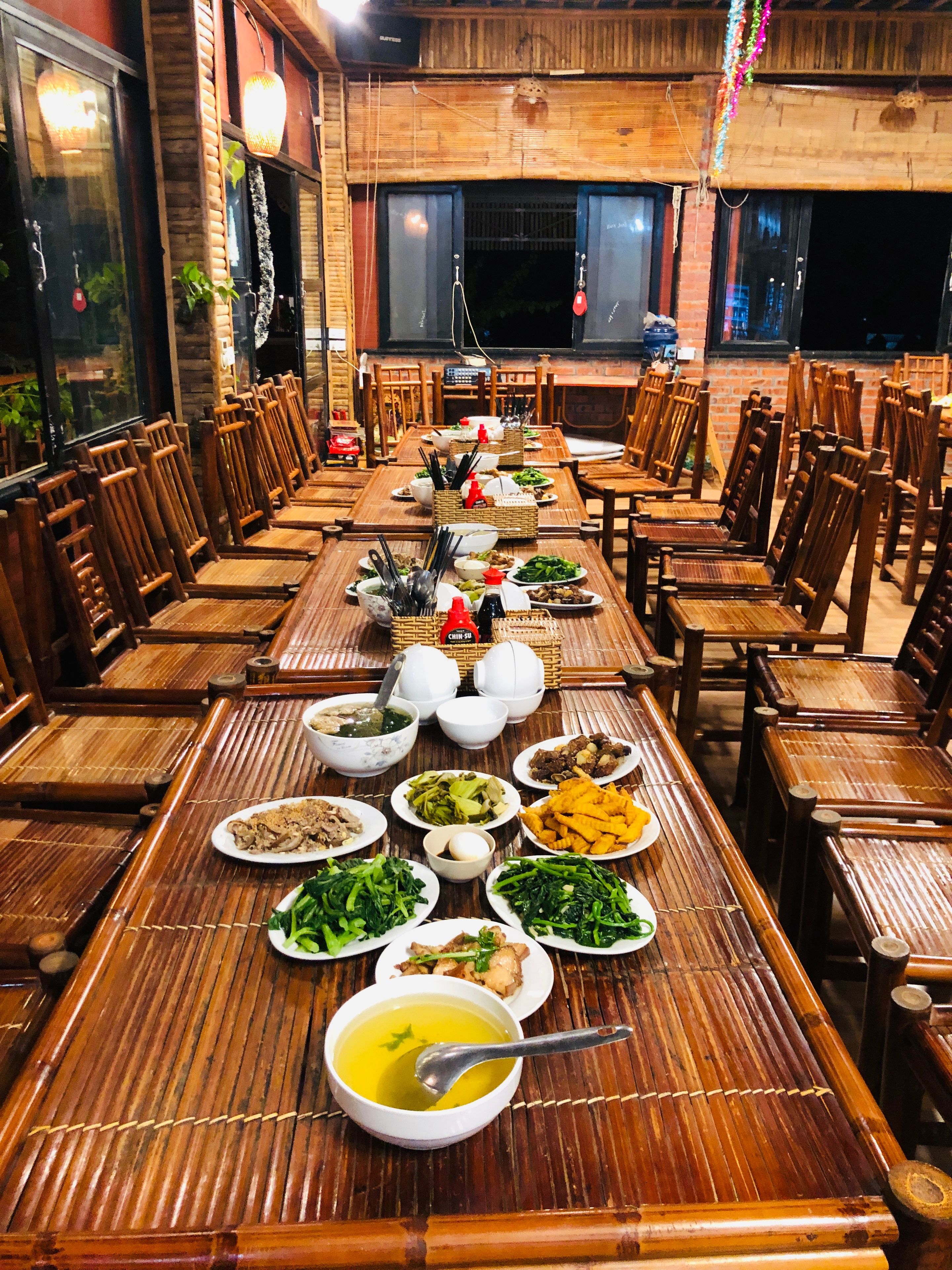 A long dining table set with various dishes, surrounded by wooden chairs.