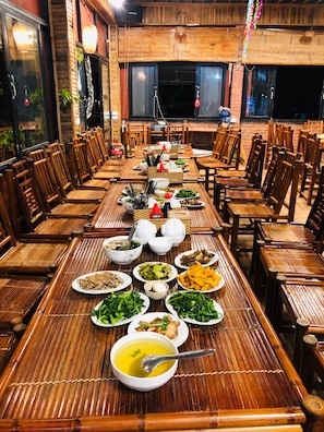 A long dining table set with various dishes, surrounded by wooden chairs. - Ninh Binh Greenland Homestay (Hoa Lu)