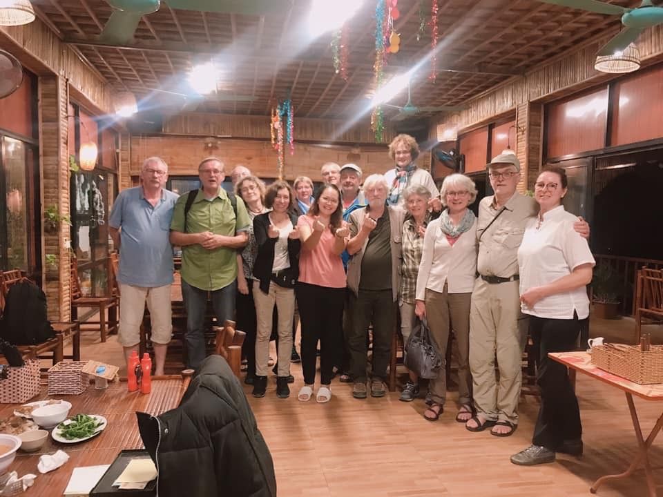 A group of people in a rustic room with wooden walls and a ceiling fan.