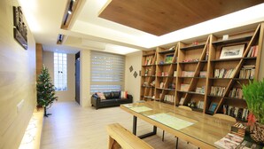 Uma biblioteca moderna com estantes de madeira, uma mesa de vidro e uma área de estar aconchegante com um pinheiro de Natal.