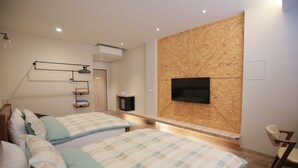 Quarto moderno com duas camas, televisão fixada na parede e um painel de madeira decorativo.