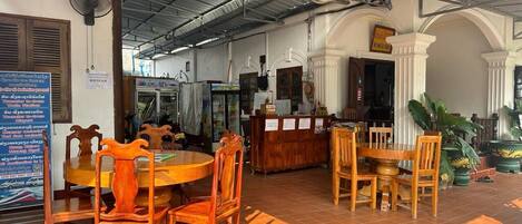 Un restaurante con mesas y sillas de madera, una barra y piso de baldosas.