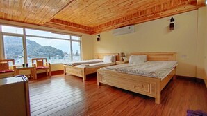 A room with two wooden beds, a desk with a chair, and a large window overlooking a scenic view. - Sa Pa Venus - Hostel (Sa Pa)