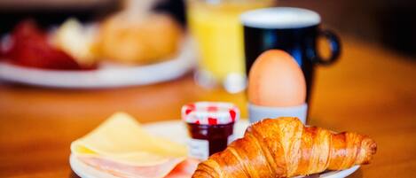 A breakfast plate with ham, cheese, a croissant, a cup of coffee, and a glass of orange juice.