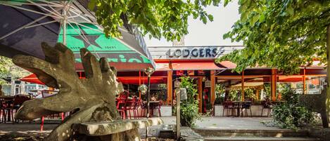 An outdoor seating area with a Heineken umbrella, a wooden sculpture, and a restaurant named 'Lodgers'.