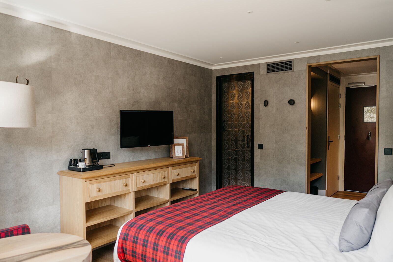 A hotel room with a bed, a TV, a desk, and a wardrobe.