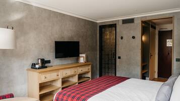 A hotel room with a bed, a TV, a desk, and a wardrobe.