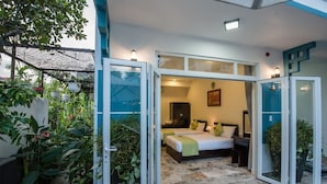 Un dormitorio con una cama, mesitas de noche y una mesita auxiliar. Se ve una ventana con vistas al exterior.