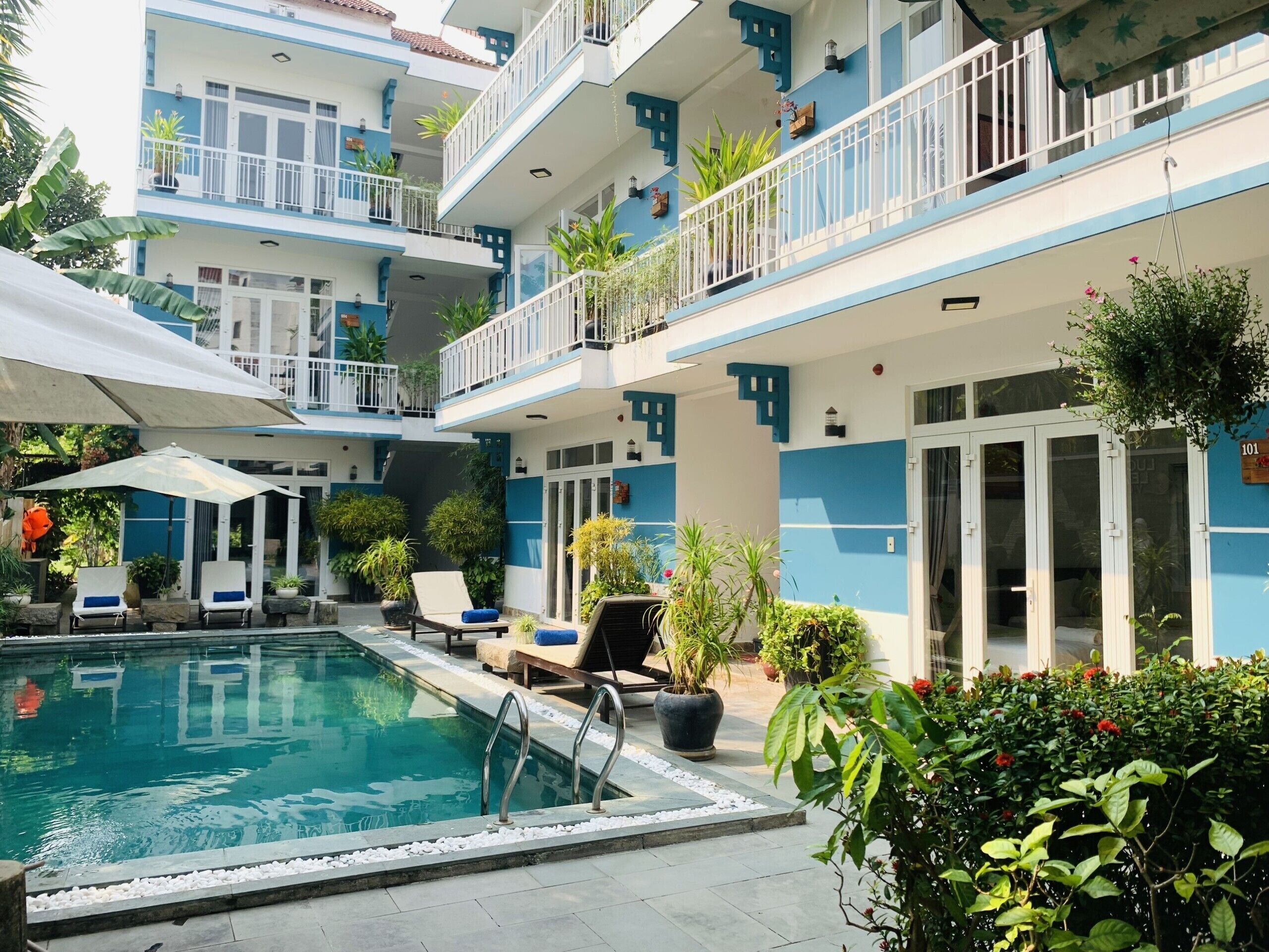 A multi-story hotel with a swimming pool, outdoor seating, and balconies.