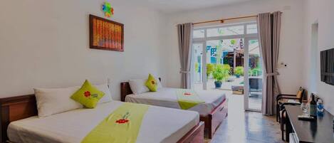 Habitación de hotel con dos camas, un escritorio y vista al exterior.