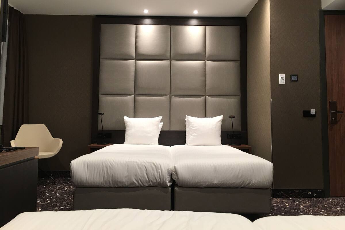 A modern hotel room with a large bed, a desk, and a chair.