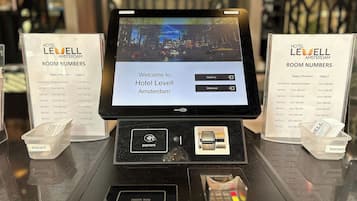 A hotel reception desk with a digital screen displaying a welcome message and room numbers.