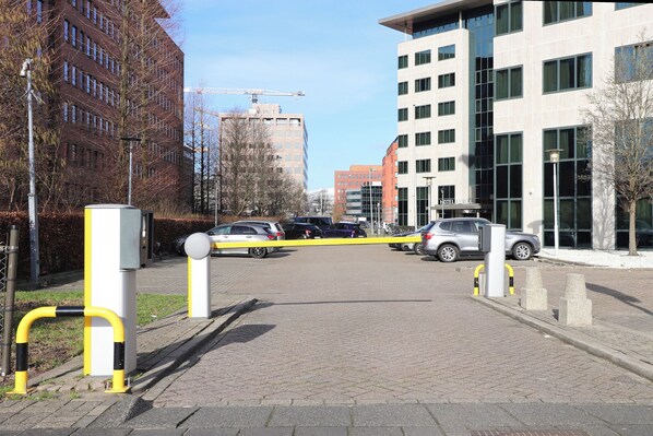 Una entrada cerrada a un hotel con un edificio moderno y coches aparcados.
