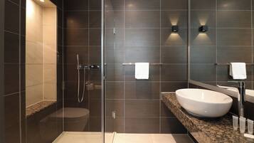Un baño moderno con ducha de vidrio, un lavamanos grande de color blanco y una encimera de mármol.
