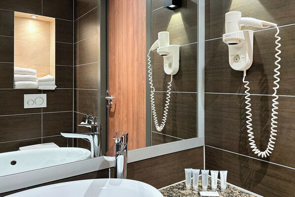 Une salle de bain moderne avec un grand miroir, un lavabo intégré, un sèche-cheveux et un porte-serviettes.