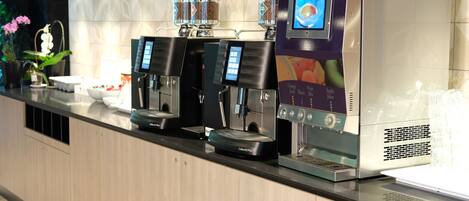 A coffee station with multiple espresso machines and a touchscreen interface.