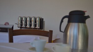 A table with a coffee maker, a box labeled "POFFADON," and a cup on a saucer. - B&B Scalea Rooms (Scalea)