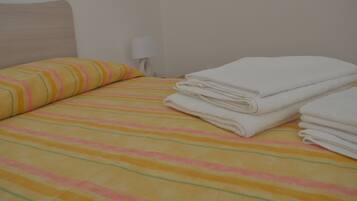 Una cama con ropa de cama a rayas, una almohada y toallas dobladas.